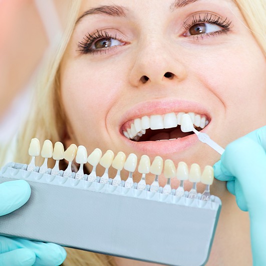 Woman's smile compared with porcelain veneer shades at cosmetic dentistry visit