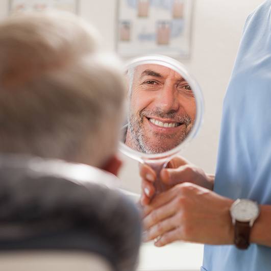 Man looking at smile after metal free dental restoration