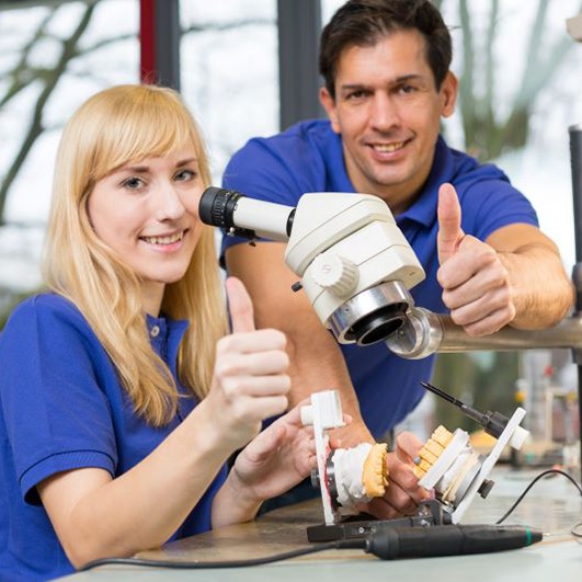 Two dental lab technicians making thumbs-up sign