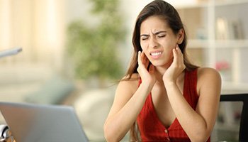 Grimacing woman experiencing TMJ pain
