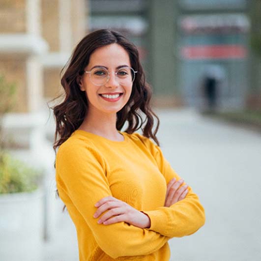 Woman with dental crown in Barnegat smiling in yellow shirt