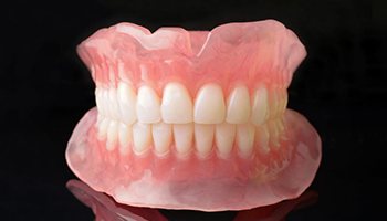 Full upper and lower dentures against dark background