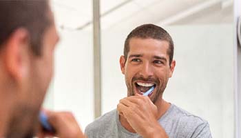 man brushing his teeth in front of a mirror