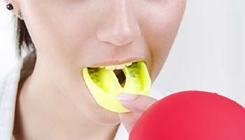 person putting a yellow mouthguard into their mouth