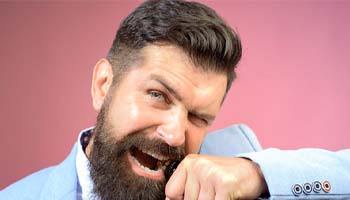 bearded man opening a glass bottle with his teeth