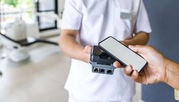 Person using phone to pay for dental treatment