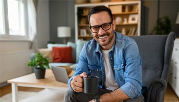 a man with dental implants smiling in his living room