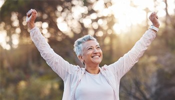 a woman with dental implants smiling outside