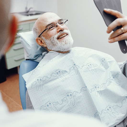 a man with dental implants smiling in his living room