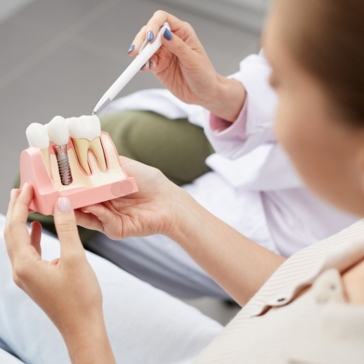 Dentist showing patient a dental implant supported tooth replacement model