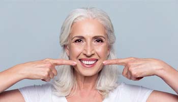 senior woman pointing to her smile