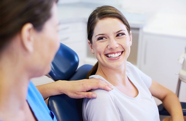 Woman in dental chair smiling at dentist