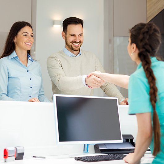 Two people checking in at dental office reception desk