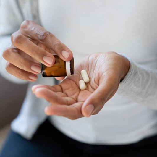 a person taking medications as per dental implant post-op instructions