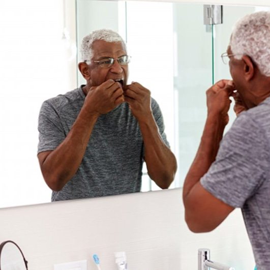 a man with dental implants flossing his teeth