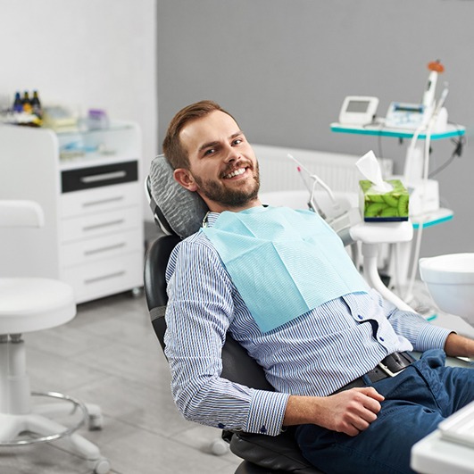 Male dental patient leaning back in chair and smiling