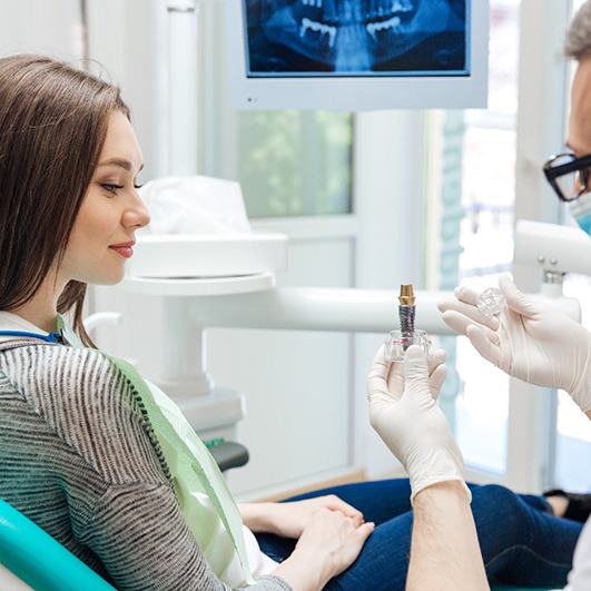 dentist showing patient a dental implant 