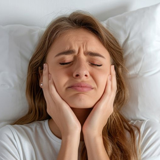 Woman lying in bed, suffering from TMJ pain