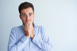 man with dental emergencies covering his mouth