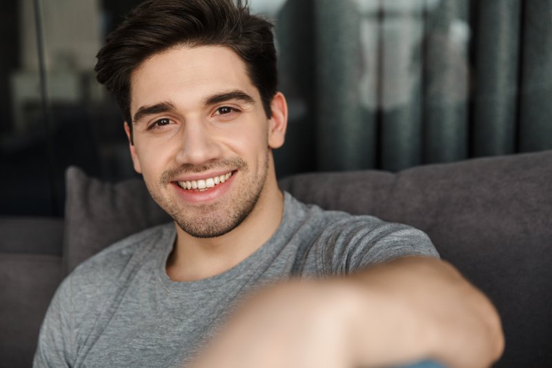  man smiling while sitting on couch 