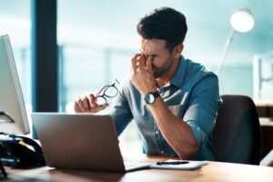 Man sitting at his desk, experiencing eye pain